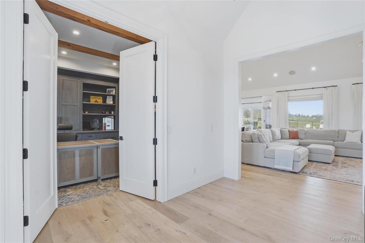 Dedicated office space featuring exposed wood beams, recessed lighting, built-in cabinetry, and a textured area rug