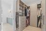 Custom closet system featuring light wood-finish shelving, integrated drawers with dark hardware, and multiple hanging rods