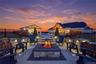Outdoor patio area featuring a built-in fire pit, stone retaining walls with integrated lighting, and paver flooring