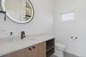Bathroom featuring a wood-finish vanity with an integrated sink, light-toned countertop, and matte black faucet