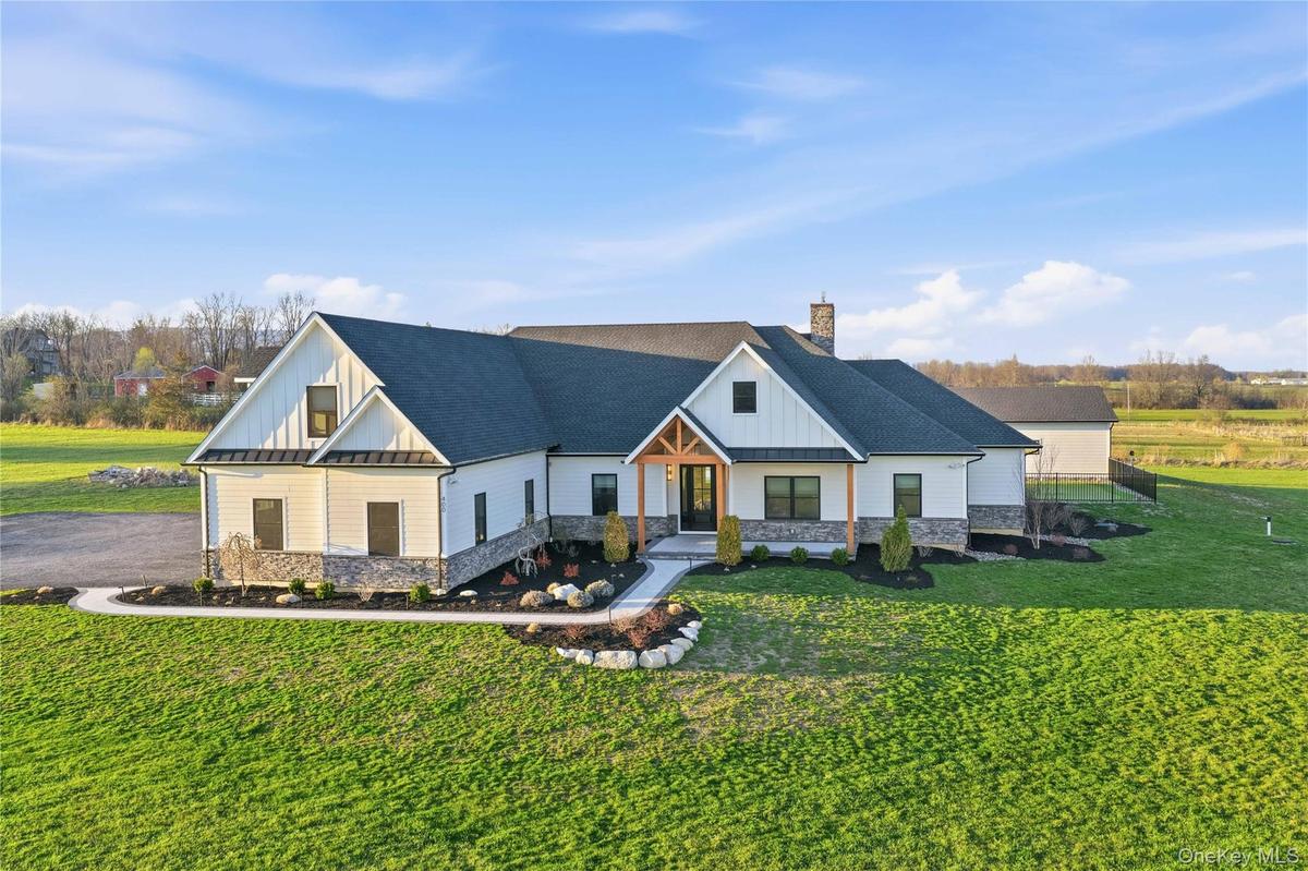 Modern farmhouse exterior featuring white board-and-batten and horizontal siding, a dark shingle roof, stone accenting, and a natural wood portico