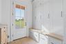 Entryway mudroom featuring white shaker-style cabinetry, wood-finish countertops, and light wood-finish flooring
