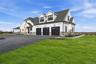 Modern farmhouse-style residence featuring white siding and dark gray stone accents