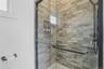 Glass-enclosed shower with matte black hardware, textured tile surround, and an integrated shower niche