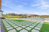 Expansive outdoor living area featuring a rectangular swimming pool, integrated sun loungers, and a paved patio with grass inlays