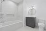 Bathroom featuring a white bathtub with subway tile surround, recessed shower niche, and chrome fixtures