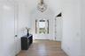 Vaulted foyer with light wood-finish flooring, a modern geometric chandelier, and a glass-paneled entry door flanked by sidelights