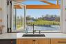 Bi-fold window opening to an outdoor pool area with a wrought iron fence