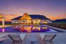 Expansive outdoor living area featuring a rectangular swimming pool with integrated lighting, a spacious patio with paver flooring, a covered outdoor 