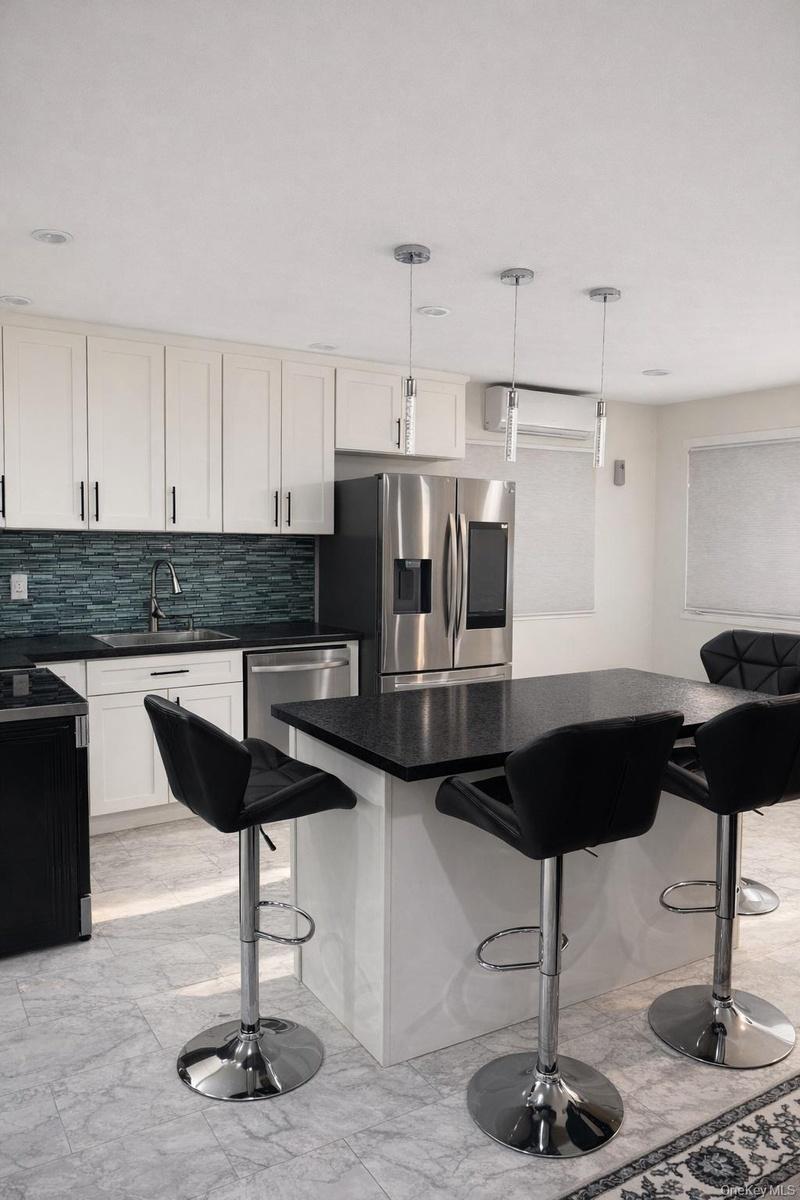 Kitchen with a kitchen bar, light marble finish flooring, pendant lighting, and tasteful backsplash