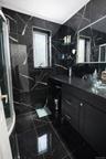 Full bathroom with vanity, a marble finish shower, tile walls, and crown molding