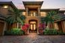 A grand arched entry with double wood doors sets the tone for the light-filled interior, where soaring ceilings, graceful lines, and generous living s