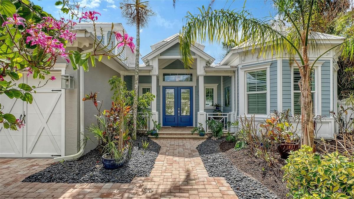 The paver driveway and walkway lead to a welcoming double French door entry