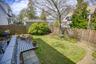 Expansive backyard featuring a gray-painted wood deck, a manicured lawn, and natural wood privacy fencing