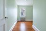 Hardwood flooring throughout a room with light green walls and white trim