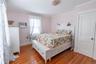 Hardwood flooring throughout bedroom featuring a window with a radiator below, a ceiling-mounted light fixture, and a white panel door