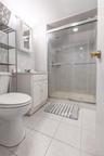 Three-quarter bathroom featuring a glass-enclosed shower, white vanity with cabinet storage, wall-mounted medicine cabinet with mirror, ceramic tile f