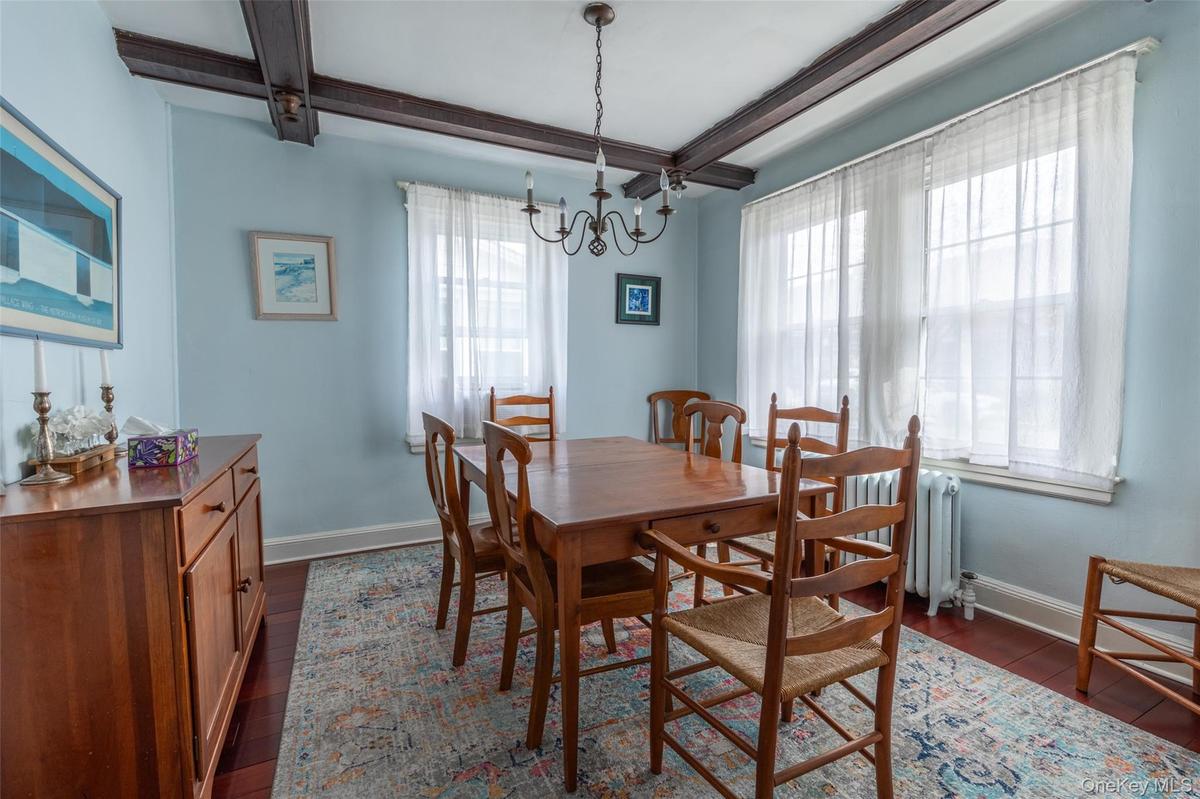 Dining area featuring exposed ceiling beams, wood-finish flooring, and multiple windows
