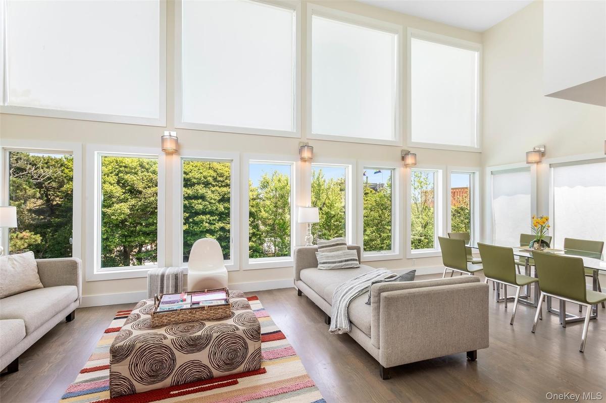 Living area with healthy amount of natural light, a high ceiling, and wood finished floors