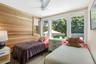Bedroom with wooden walls, ceiling fan, and wood finished floors