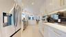 Modern kitchen featuring white cabinetry with gold-tone hardware, stainless steel appliances, and a dark stone backsplash