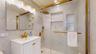 Bathroom featuring a white vanity with gold-tone hardware, a gold-tone faucet, and a mirrored medicine cabinet with integrated lighting
