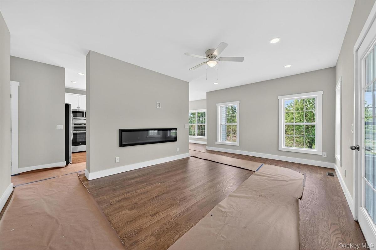 Another view of the open floor plan of the family room with hardwood flooring and the fireplace.