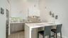 Contemporary kitchen with solid surface countertops and waterfall-edge island and SS appliances, including Miele induction range & Miele d/w, hood, an