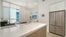 Contemporary kitchen with solid surface countertops and waterfall-edge island and SS appliances, including Miele induction range & Miele d/w, hood, an