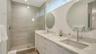 Roomy modern  bathroom with dual sinks and private toilet room.