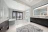 It features dual expansive vanities, square sinks, custom tile backsplash, backlit mirrors with integrated TV feature.