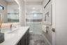 The bathroom has a large vanity, backlit mirror and walk-in shower with glass shower door.