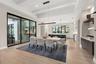The adjacent dining room is refined, featuring a Schonbek Beyond Mystique LED linear pendant and glass sliding doors with access to the outdoor kitche