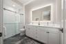 The en-suite bathroom has a double vanity, backlit mirror, porcelain tile flooring and walk-in shower with glass door.