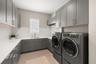 Even the laundry room has been elevated to designer quality with custom wood cabinetry, quartz countertops, tile backsplash, sink with views overlooki