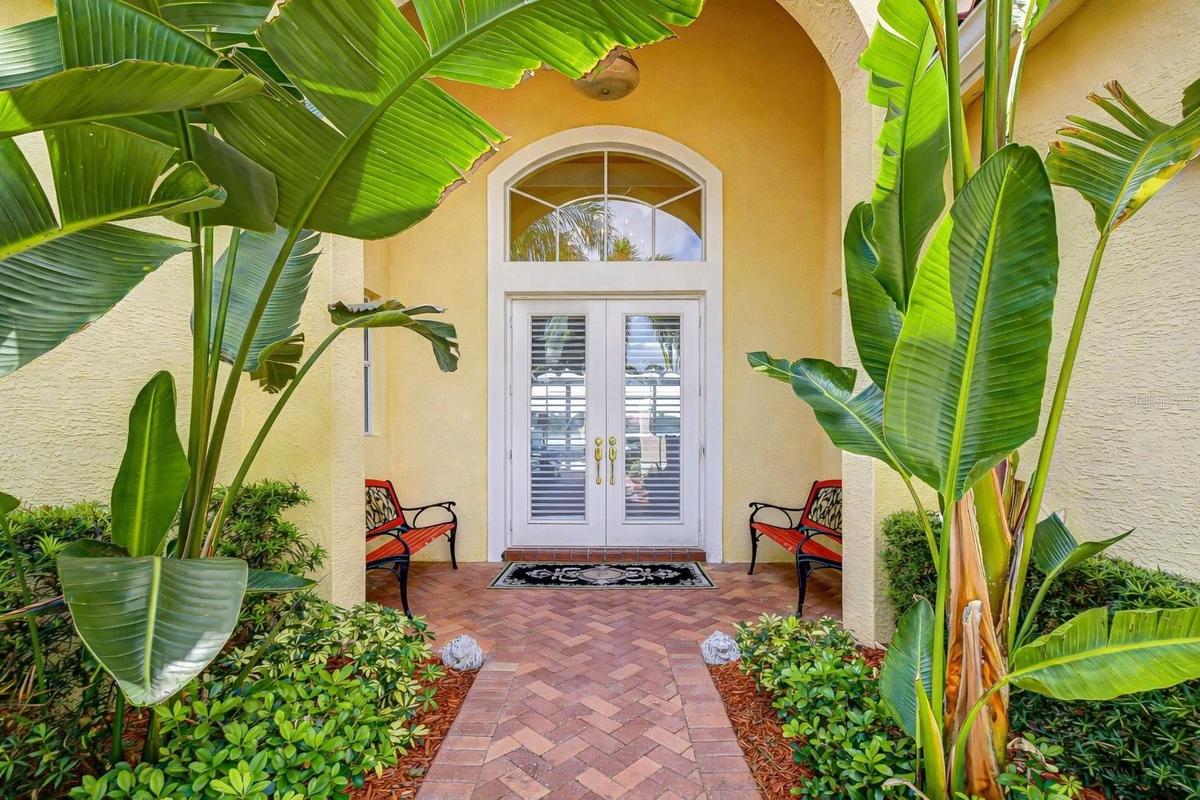 Elegant curb appeal featuring a tile roof and tropical landscaping