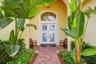 Elegant curb appeal featuring a tile roof and tropical landscaping