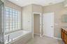 The primary bathroom features a private water closet and glass block windows that provide natural light while maintaining privacy.