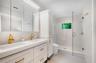 Primary ensuite bathroom with custom cabinetry, dual sinks, high end fixtures and toilet and beautifully tiled shower