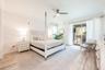 The main-level Primary Suite is a serene escape, showcasing LUXURY VINYL PLANK FLOORING, private sliding doors to the pool area, and a spa-inspired en