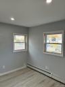 Unfurnished room featuring a baseboard heating unit, recessed lighting, light wood-type flooring, and healthy amount of natural light