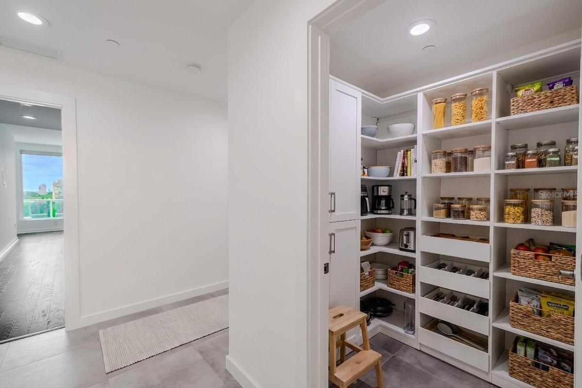 Spacious walk-in pantry with custom built-in shelving, ample storage, and pull-out drawers for easy organization. Clean white cabinetry and adjustable