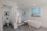 The luxurious primary bathroom exudes spa-like serenity with a sleek, modern design. A private water closet, a freestanding soaking tub serves as the 