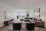 This bright and spacious dining and living area offers an elegant, open layout with sleek tile flooring and contemporary lighting. Floor-to-ceiling gl