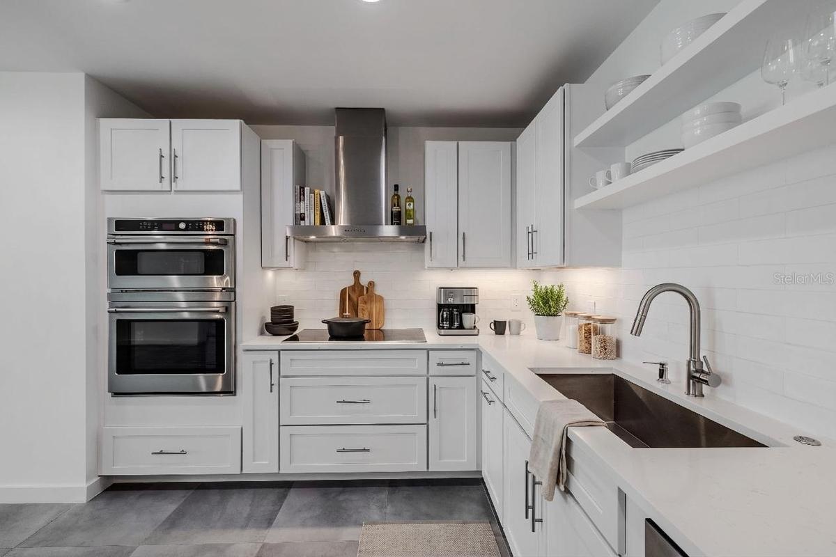 High-end stainless-steel appliances include a French door refrigerator, dishwasher, double wall ovens, and a vent hood. Large  tile floors and under-c