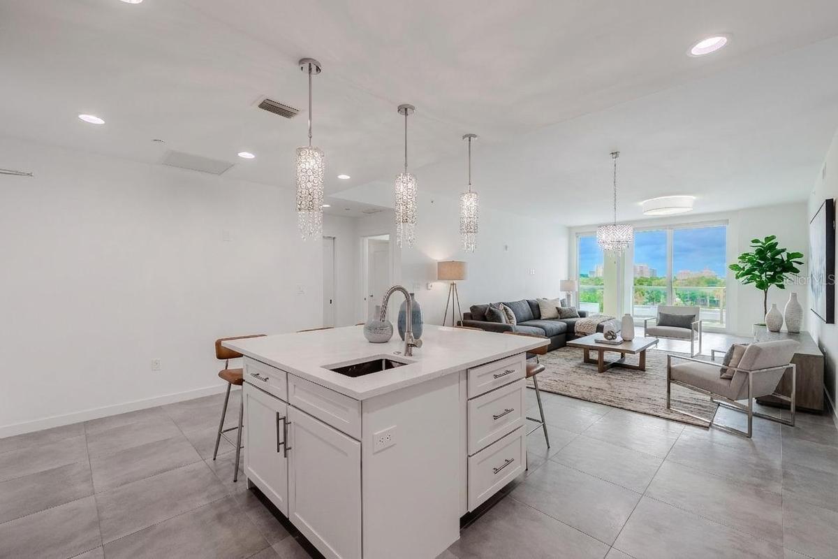 From the kitchen, enjoy an open-concept view that seamlessly connects the dining and living areas. Sleek tile flooring and designer lighting create a 