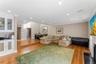 Open-concept living space featuring wood-finish flooring, a built-in wet bar with glass-front cabinetry and a dark countertop, recessed ceiling lighti