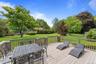 Spacious outdoor deck with wood-finish flooring and a wood railing overlooking an expansive manicured lawn