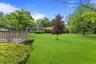 Expansive green lawn with mature trees and perimeter landscaping
