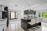 Kitchen with light marble finish flooring, recessed lighting, glass insert cabinets, pendant lighting, and wall chimney exhaust hood